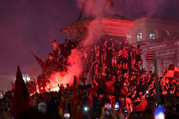 AC Milan fans celebrate by the statue of Vittorio Emanuele II at Piazza