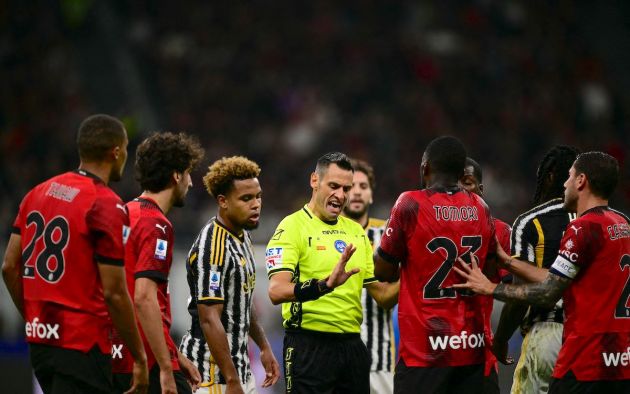 Referee Maurizio Mariani argues with AC Milan's players
